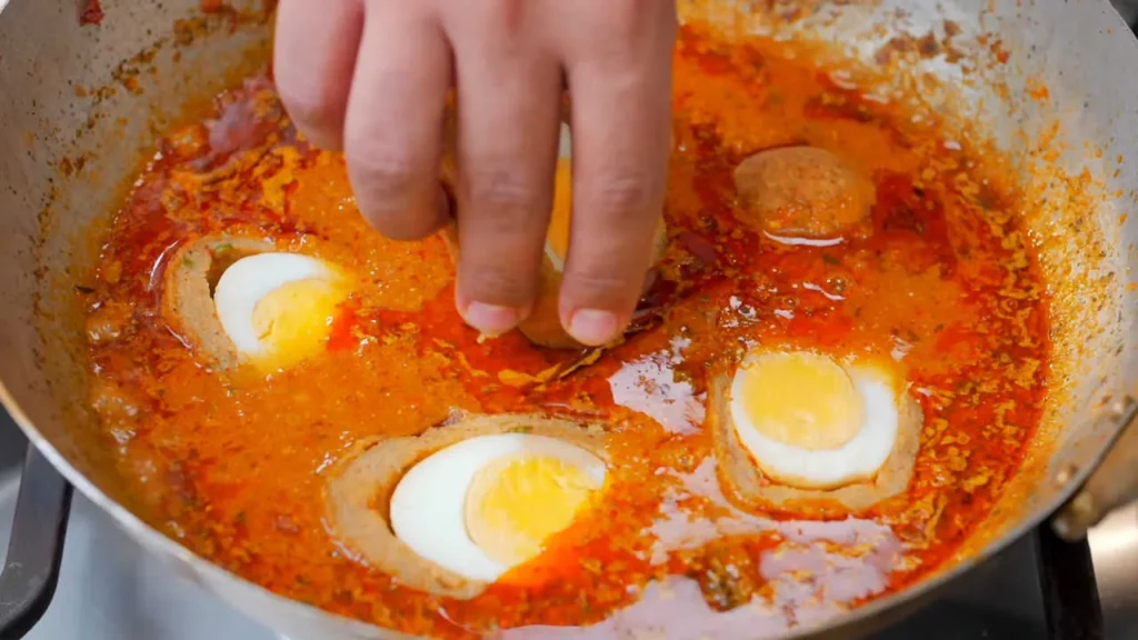 Adding fried kofta into the hot gravy